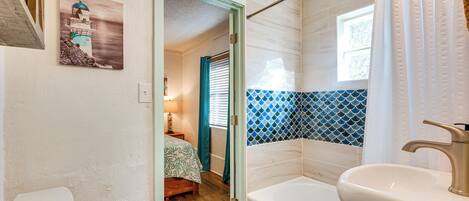 A bathroom with a bathtub, two sinks, and a door leading to a bedroom.