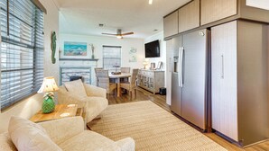 A living room with a sofa, a coffee table, and a dining area with a table and chairs. There is a kitchen with a refrigerator and cabinets. - < 1 Mi to Beach: Family-friendly Port St Joe Home (Port St. Joe)