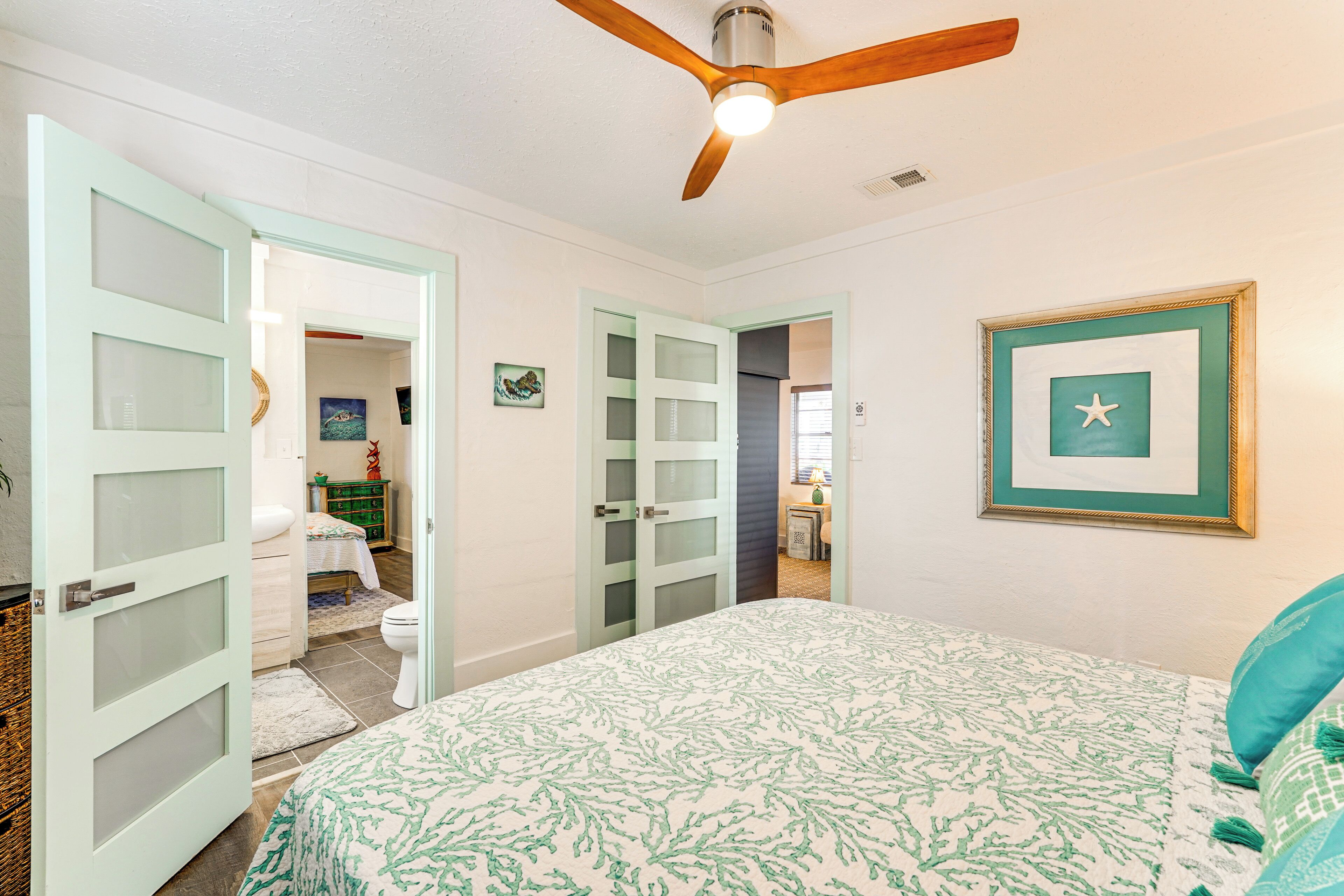 A bedroom with a bed, a ceiling fan, and a framed picture on the wall.