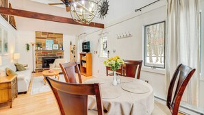 Ein geräumiges Wohnzimmer mit Kamin, Holzmöbeln und einem Essbereich mit rundem Tisch und Stühlen.