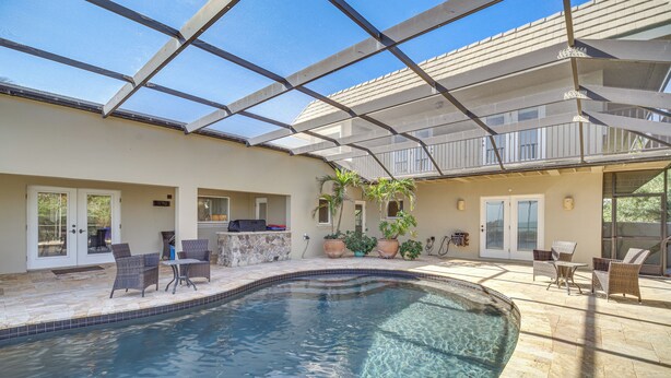 A swimming pool with clear water, surrounded by outdoor furniture and potted plants. - Beachfront Melbourne Beach Retreat w/ Pool Table! (Melbourne Beach)