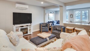 A living room with a TV, seating, and a kitchen area with stools. - 1 Mi to Drakes Island Beach: Cottage w/ Deck! (Wells)
