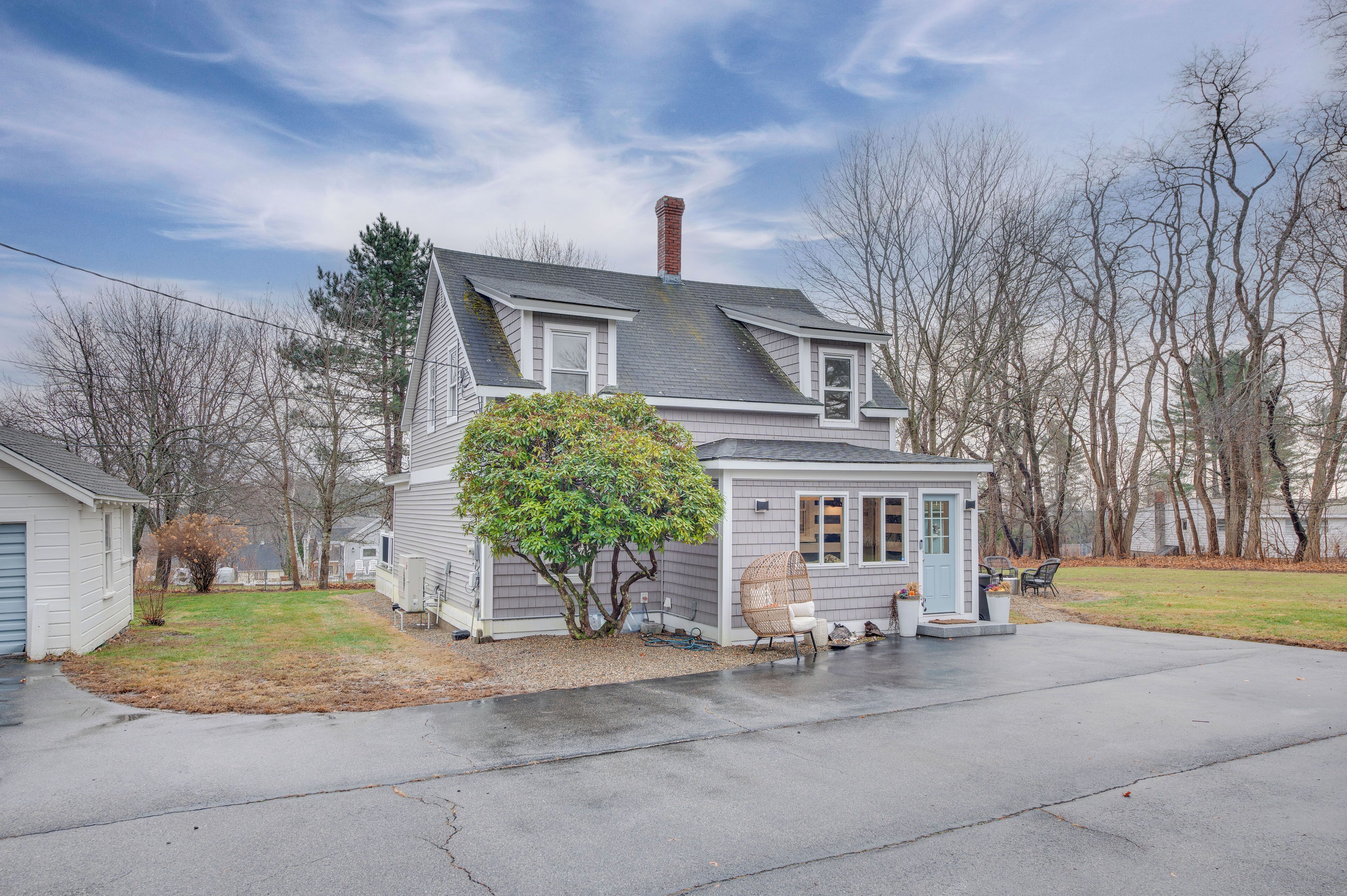A two-story house with a covered porch, a chimney, and a small garden area.