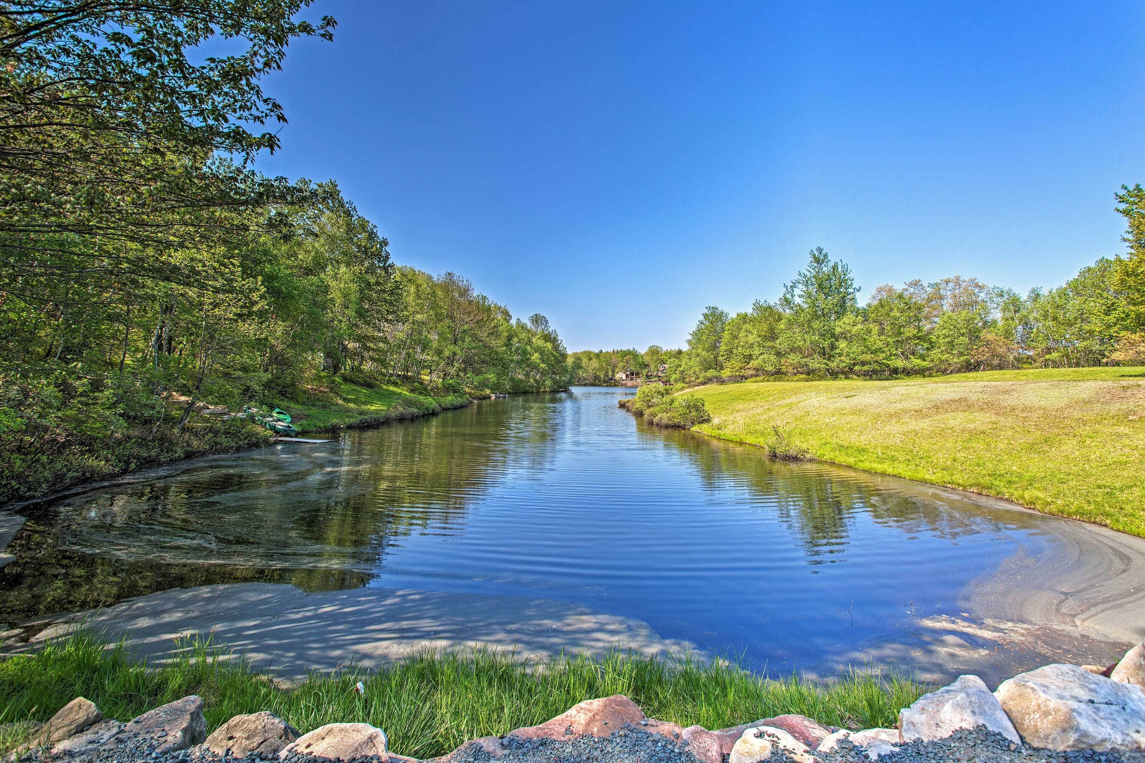 A calm river with a grassy bank and trees on both sides.