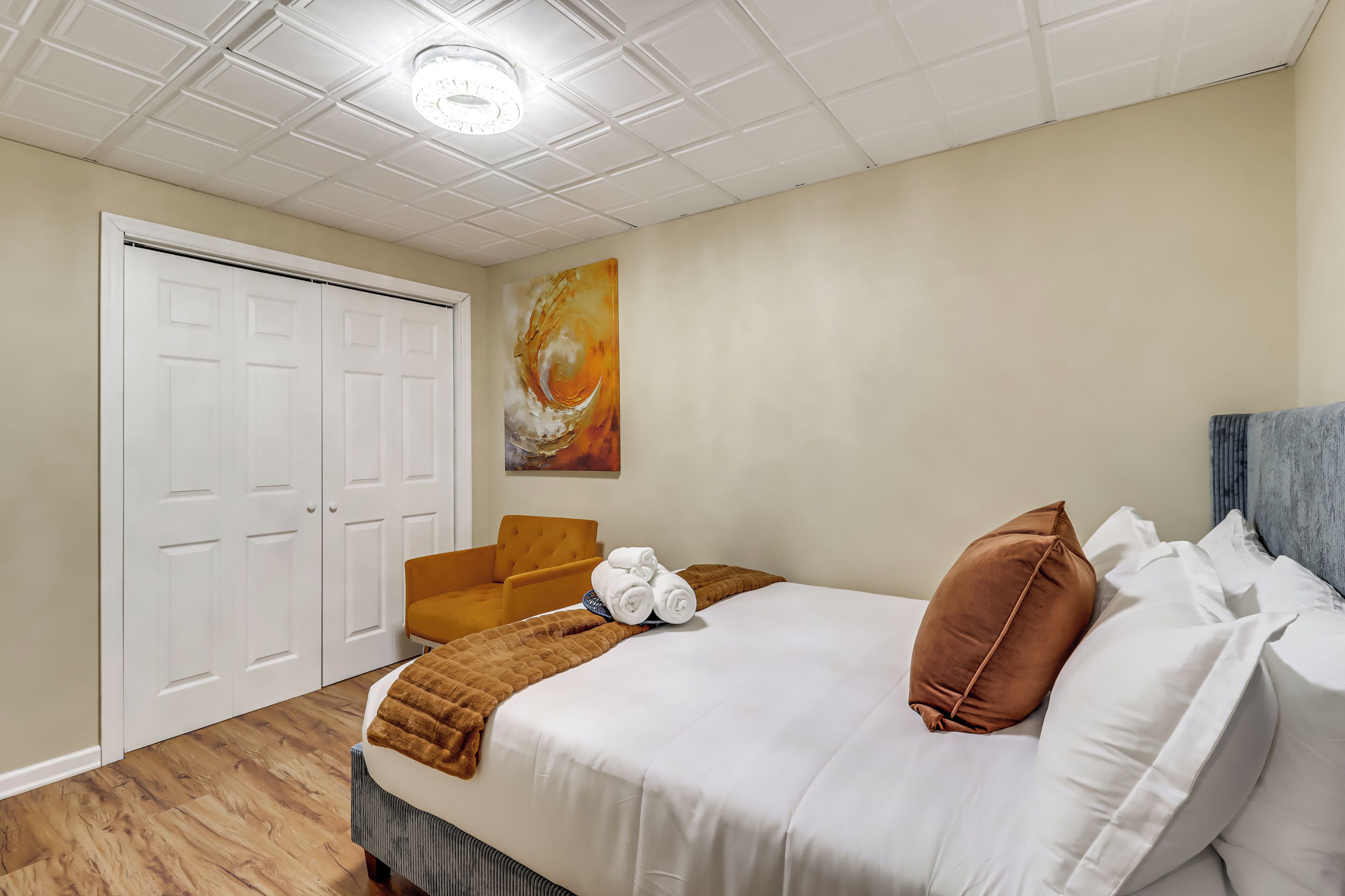 Een hotelkamer met een groot bed, een stoel, een schilderij aan de muur en een deur.