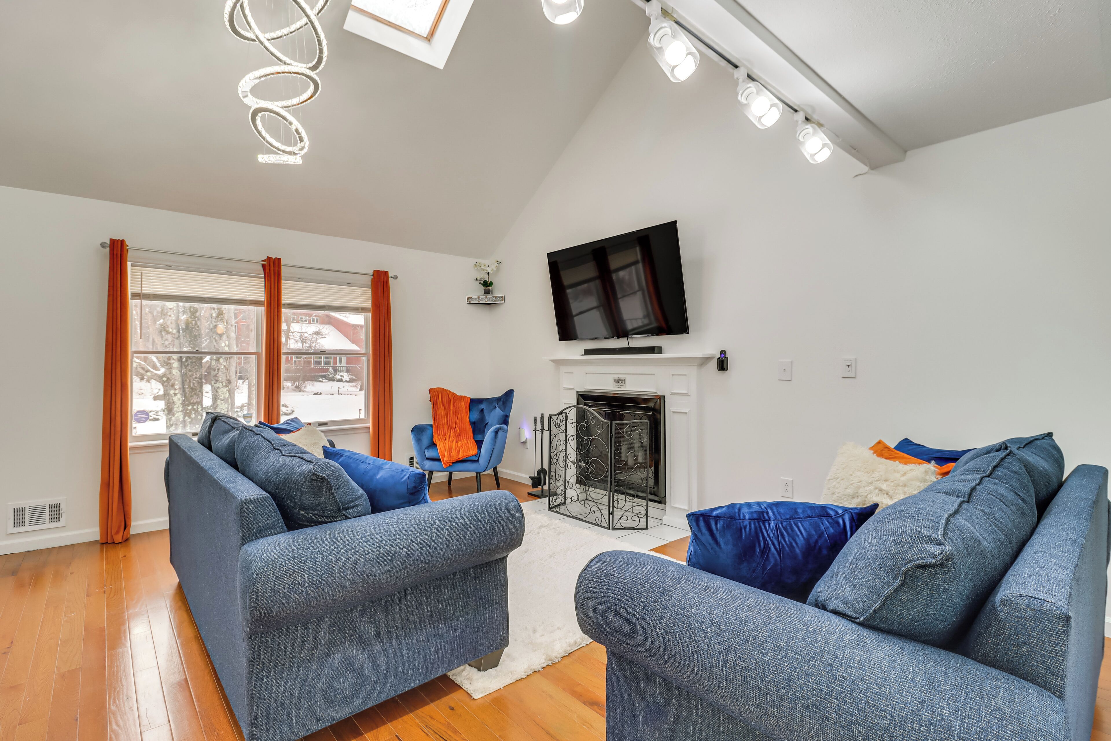 Una sala de estar moderna con chimenea, sofás azules y un televisor.