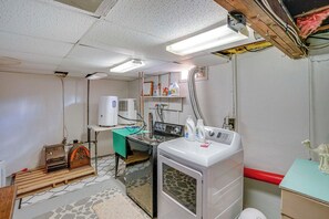 Laundry room with vintage washing machine, modern dryer, and workbench.