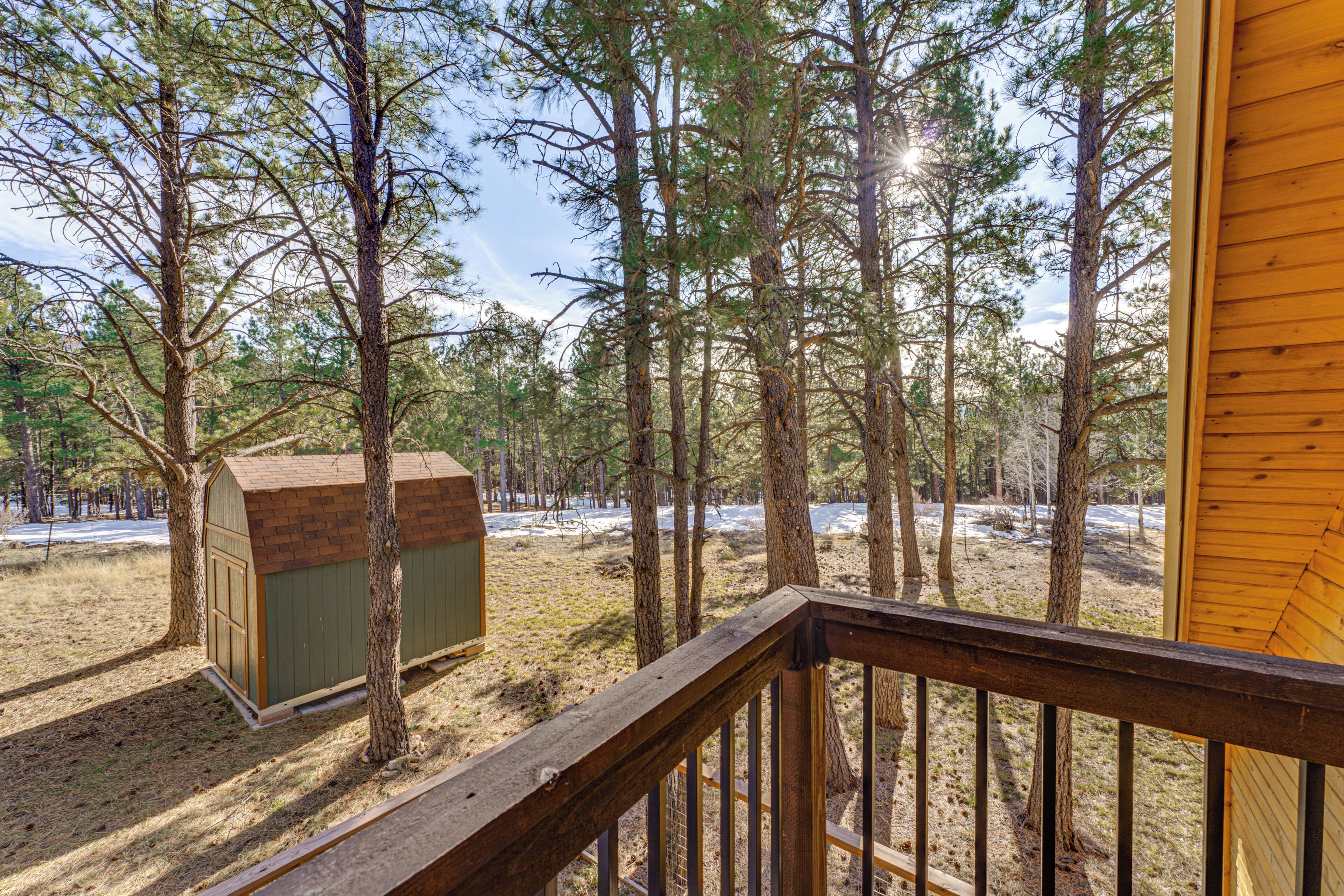 A wooden deck with a view of a forested area and a small shed.