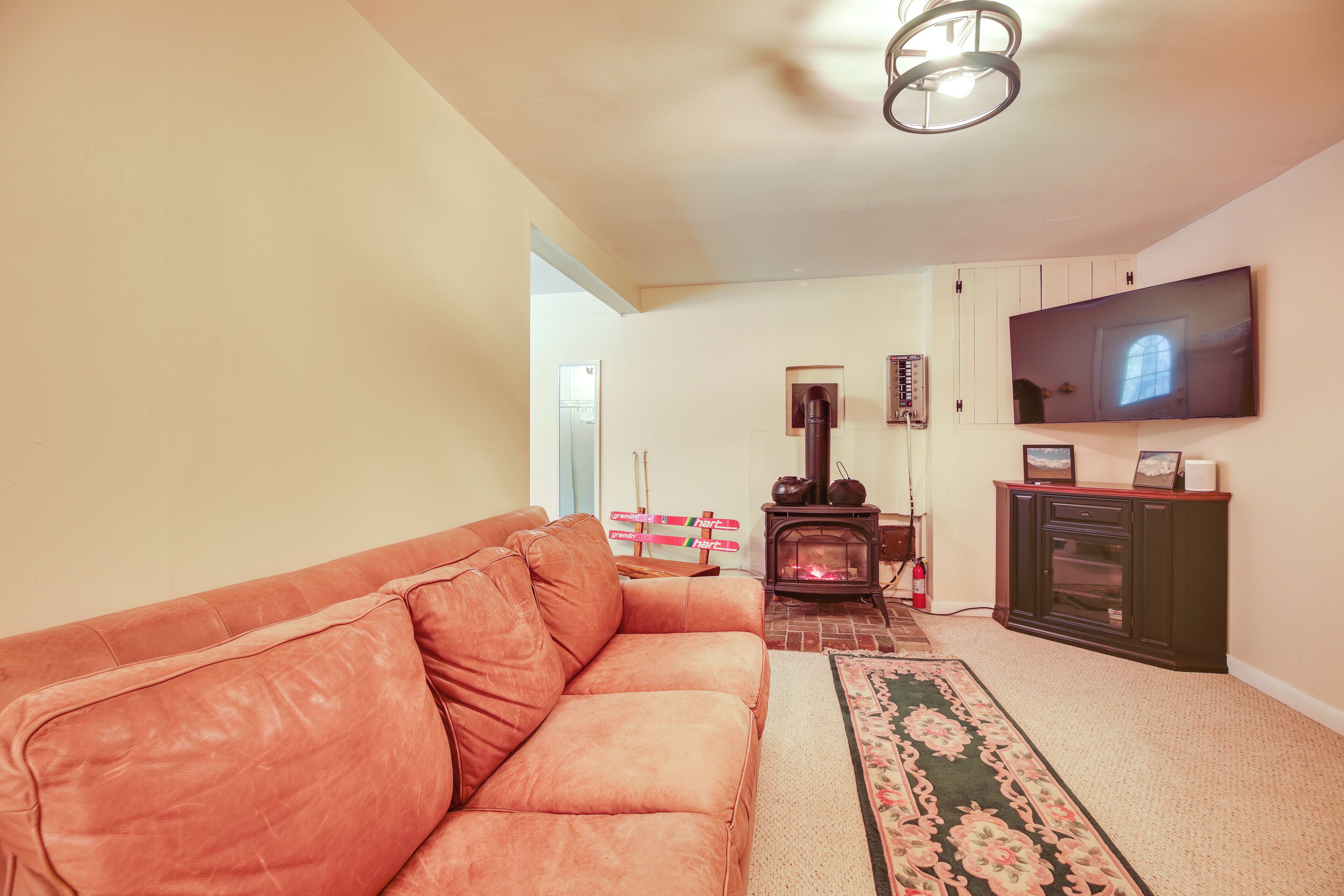 A living room with a leather sofa, a fireplace, a television, and a cabinet.