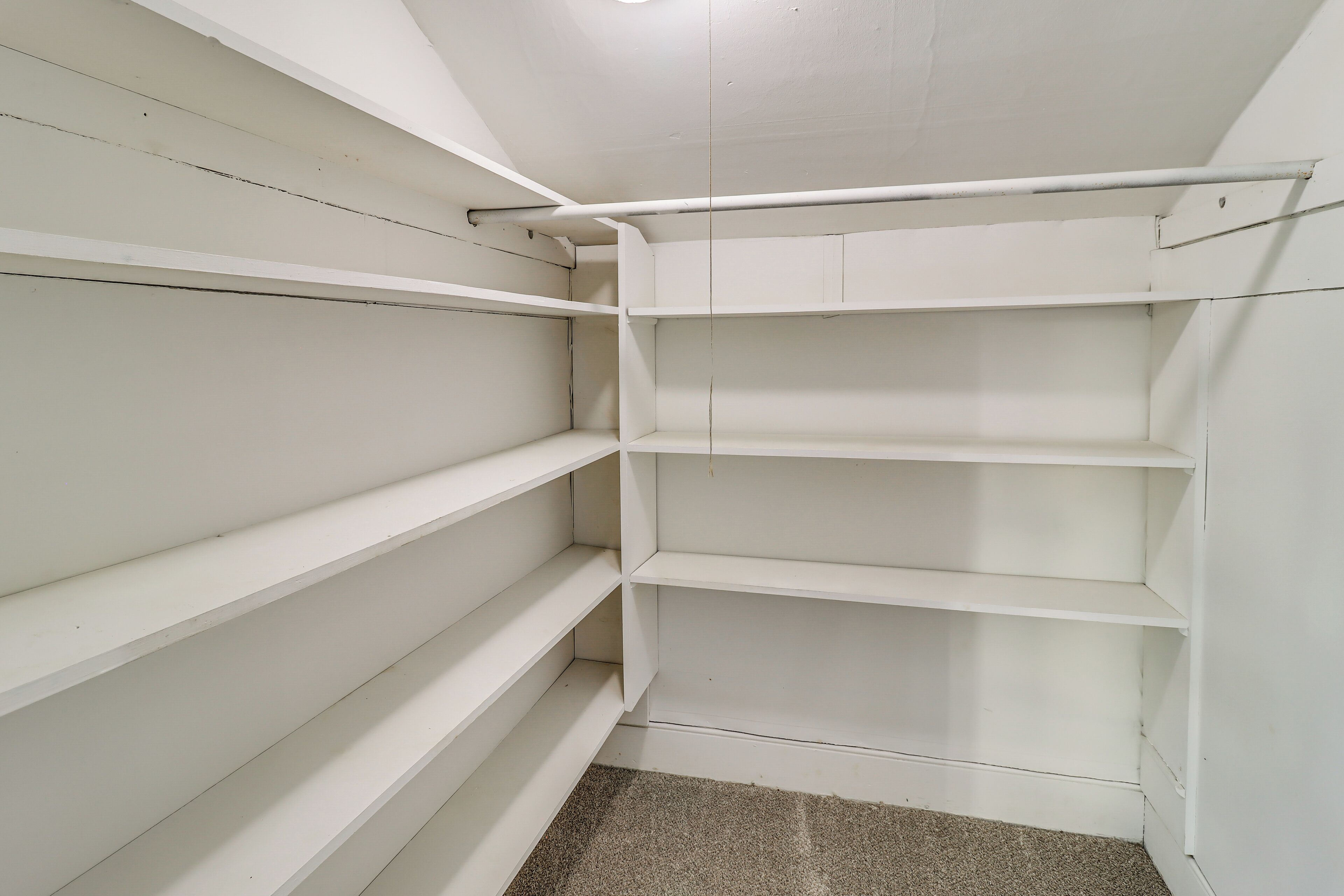 A white closet with multiple shelves and hanging space.