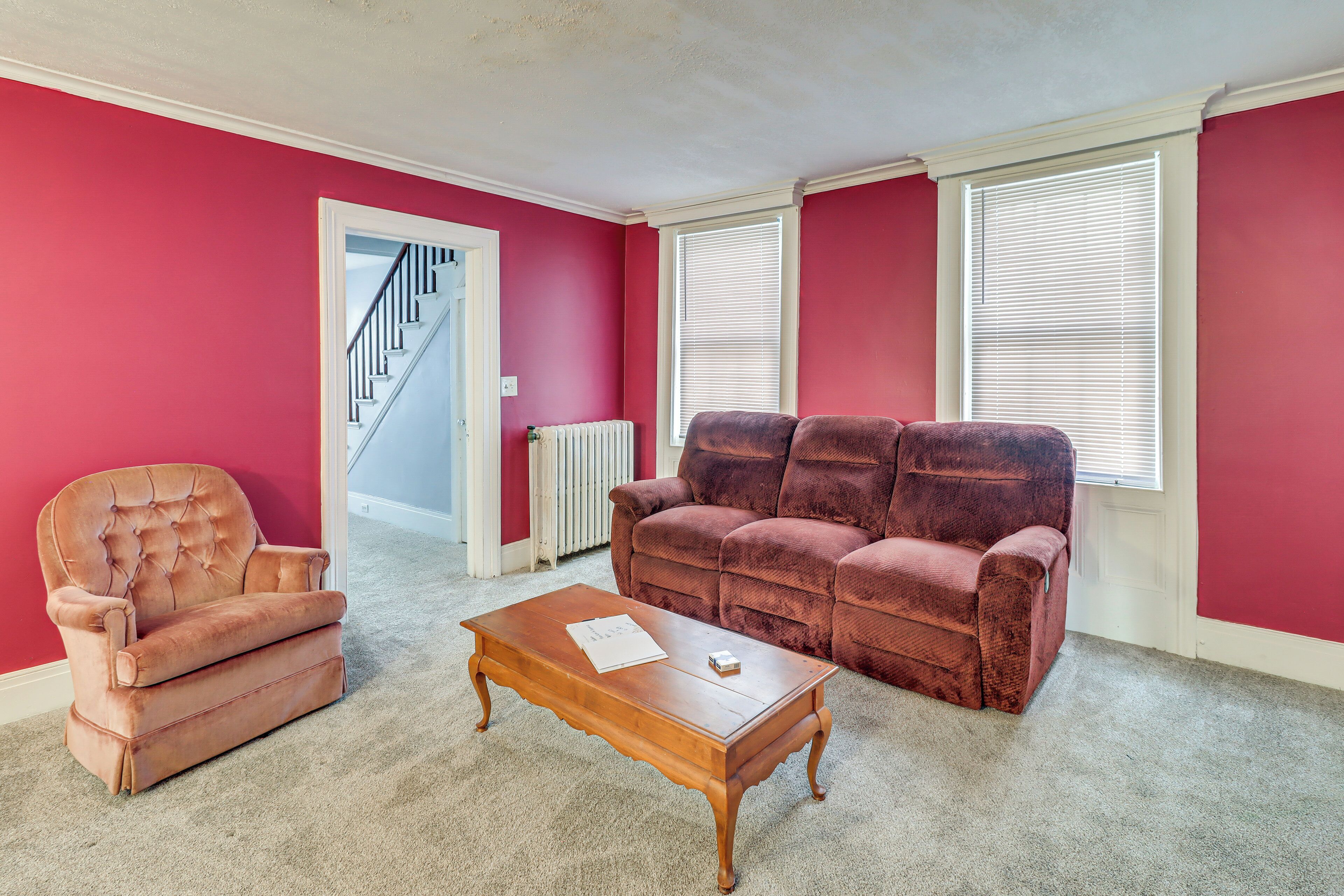 A living room with a red wall, a brown sofa, a brown armchair, and a wooden coffee table.