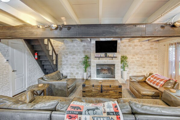 Ein modernes Wohnzimmer mit Ledersofas, einem Holztisch und einem Kamin.