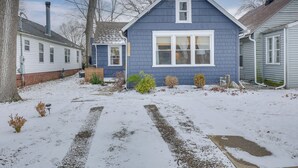 Un quartier résidentiel avec une maison bleue, une maison blanche et une cheminée.