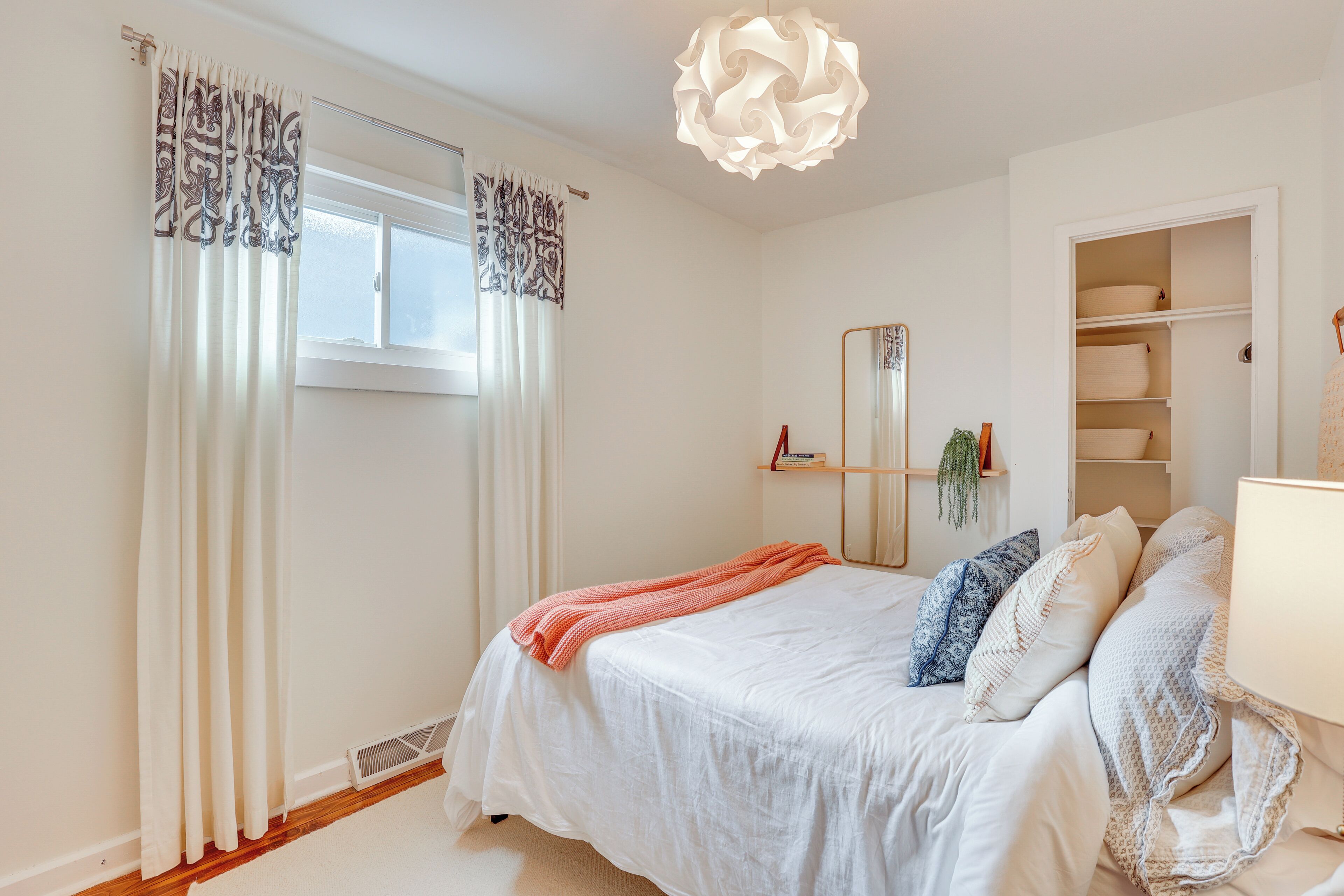 Un dormitorio con cama, mesita de noche, espejo y armario.