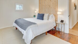 Une chambre à coucher avec un lit, des lampes de chevet, une petite table, une fenêtre et un mur recouvert de lambris en bois.