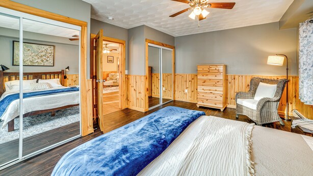 Une chambre à coucher avec un grand lit, une chaise, une commode et un ventilateur de plafond.