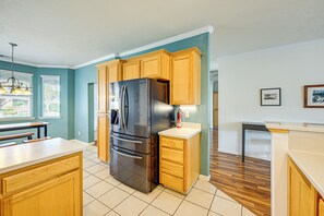 A kitchen with wooden cabinets, a stainless steel refrigerator, and a white countertop. - 26 Mi to Fresno: Pet-friendly Home in Reedley! (Reedley)