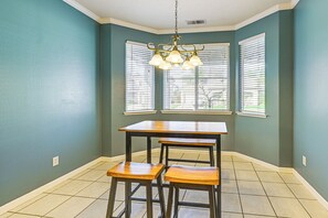 A dining area with a table and two stools, a chandelier, and large windows with blinds. - 26 Mi to Fresno: Pet-friendly Home in Reedley! (Reedley)