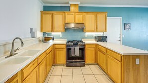 A kitchen with wooden cabinets, a stainless steel stove, a microwave, and a sink. - 26 Mi to Fresno: Pet-friendly Home in Reedley! (Reedley)