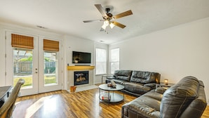 A living room with a fireplace, leather sofa, and a ceiling fan. - 26 Mi to Fresno: Pet-friendly Home in Reedley! (Reedley)