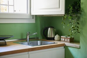 A kitchen with a stainless steel sink, a kettle, a plant, and a 'HOME' sign on the wall. - Casa Hugo, studio apartment in San Niccolò district (Firenze)