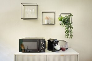 A kitchenette with a microwave, coffee maker, and framed pictures on the wall. - Casa Hugo, studio apartment in San Niccolò district (Firenze)