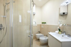 A modern bathroom with a glass-enclosed shower, a toilet, bidet, and a sink with a mirror above. - Casa Hugo, studio apartment in San Niccolò district (Firenze)