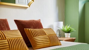 A neatly made bed with a green quilt, two brown pillows, and a small potted plant on a wooden nightstand. - Casa Hugo, studio apartment in San Niccolò district (Firenze)