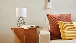 A wooden bedside table with a lamp, an open book, and a cushion on a white sofa. - Casa Hugo, studio apartment in San Niccolò district (Firenze)