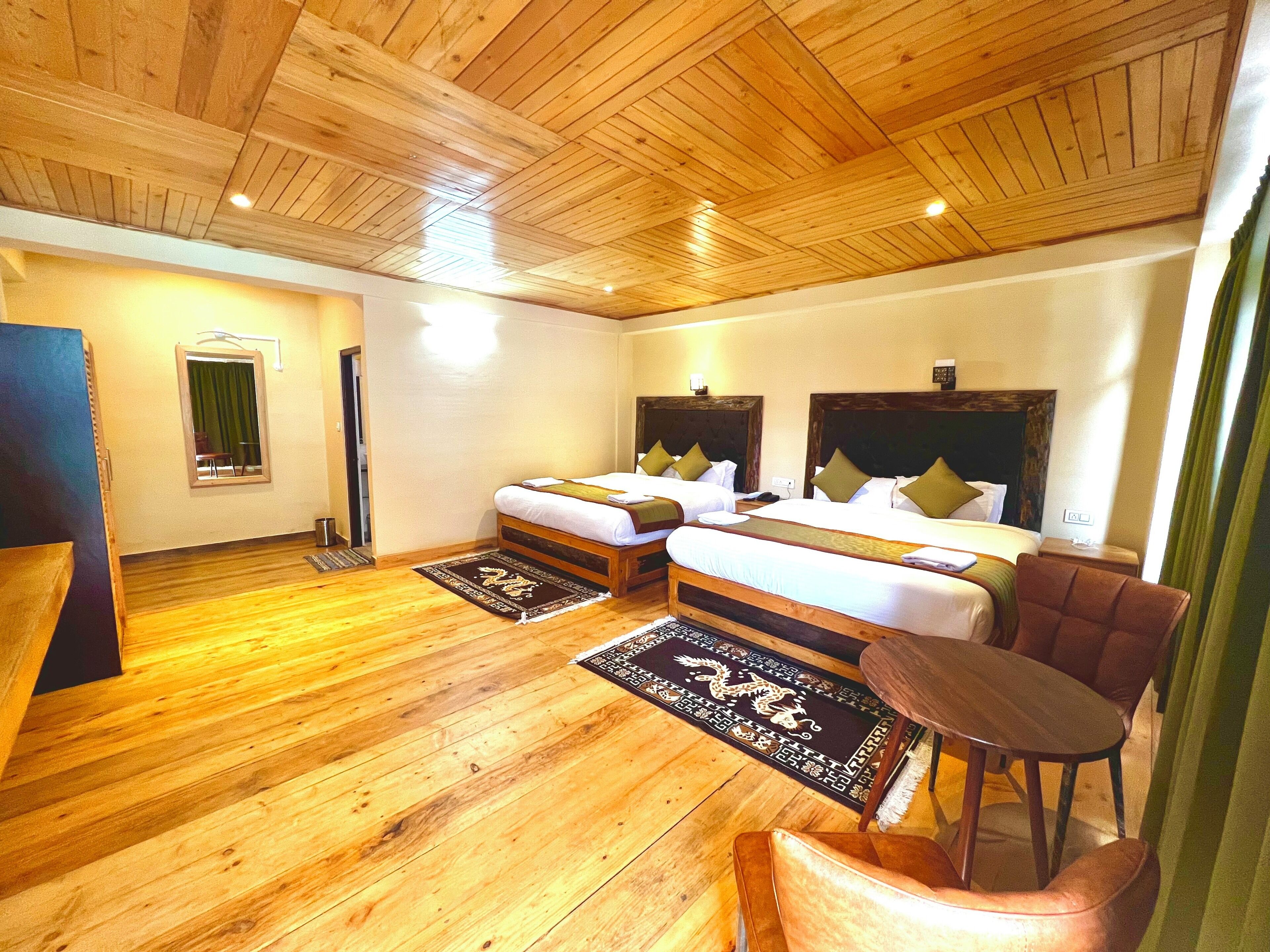 Une chambre d’hôtel avec deux lits, un plancher en bois, une petite table et une chaise.