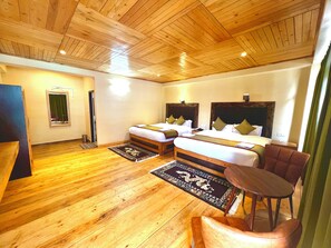 A hotel room with two beds, a wooden floor, a small table, and a chair. - The Country House (Chungthang)