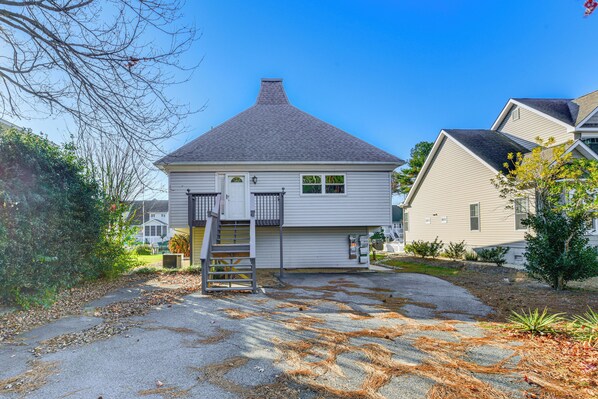A two-story house with a grey roof, a front yard with a driveway, and a small garden area. - Furnished Deck! Waterfront Ocean Pines Home (Berlin)