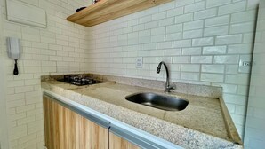 A kitchen with white subway tiles, a granite countertop, a stainless steel sink, and a gas stove.