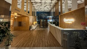 A modern reception area with a wooden reception desk, a ceiling with circular patterns, and a marble floor. - RentPlanet - Apartamenty Quorum (Wroclaw)