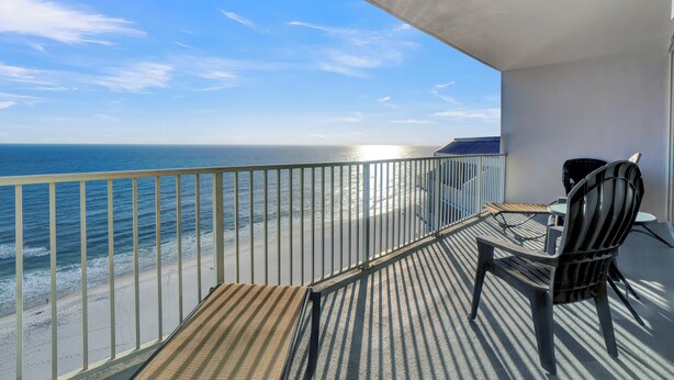 Ein Balkon mit Blick auf das Meer, ein Stuhl und ein kleiner Tisch.