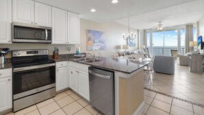 A modern kitchen with white cabinets, stainless steel appliances, and a large island with a sink.