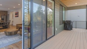 A modern kitchen with wooden cabinets, a dining area with a table and chairs, and a large sliding glass door leading to an outdoor deck. - cabin, hot tub! 3rd night free stay before 9/8/26 (Government Camp)
