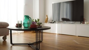 A modern living room with a round black metal table, a flat-screen TV mounted on the wall, and a wooden floor. - Pet friendly home in Liznjan (Liznjan)