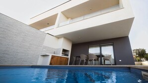 A modern building with a swimming pool, a dining area with chairs, and a kitchen area. - Pet friendly home in Liznjan (Liznjan)