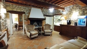 A rustic interior with stone walls, a fireplace, wooden furniture, and a television. - Campo Al Vento (Monte Castello di Vibio)