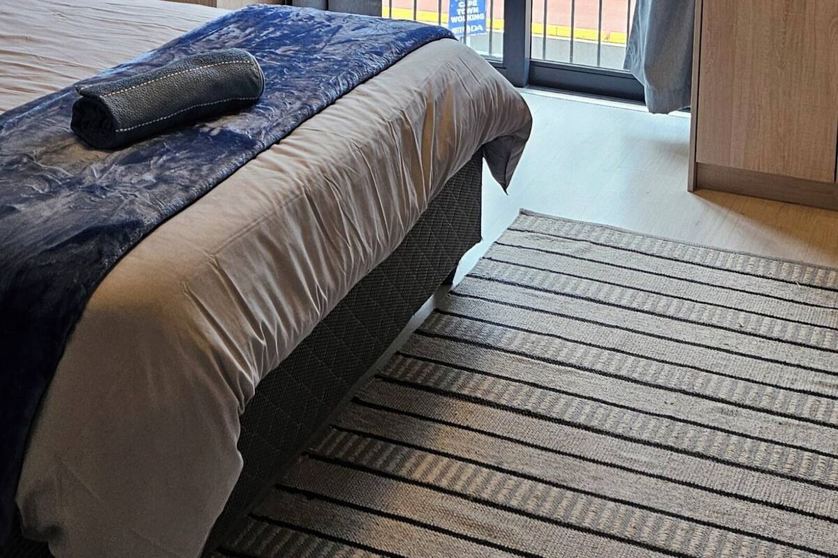A hotel room with a bed, a window with curtains, a view of the outside, and a door.