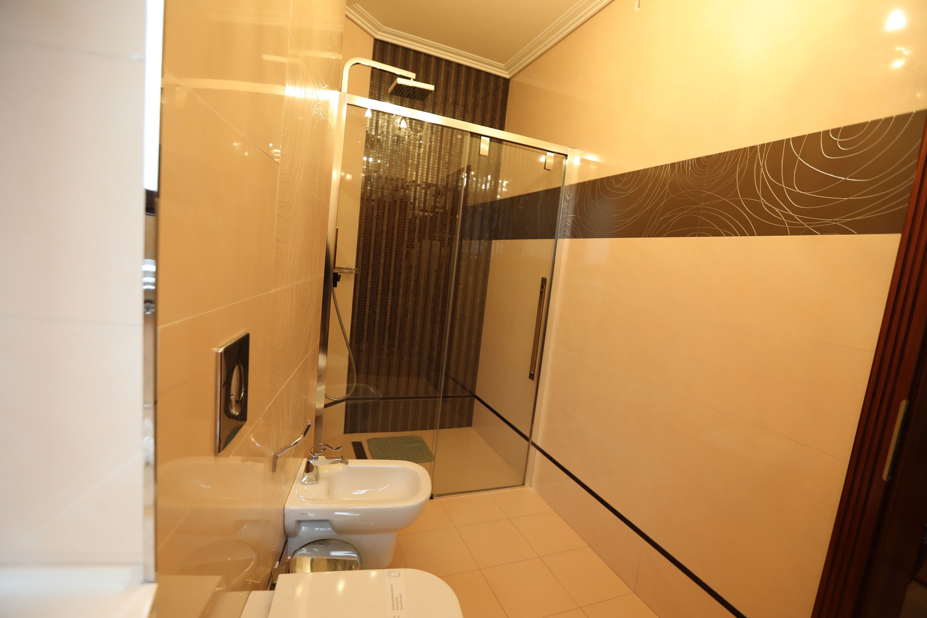 Un baño moderno con ducha de mampara de vidrio, inodoro y lavamanos.