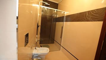 Un baño moderno con ducha de mampara de vidrio, inodoro y lavamanos.