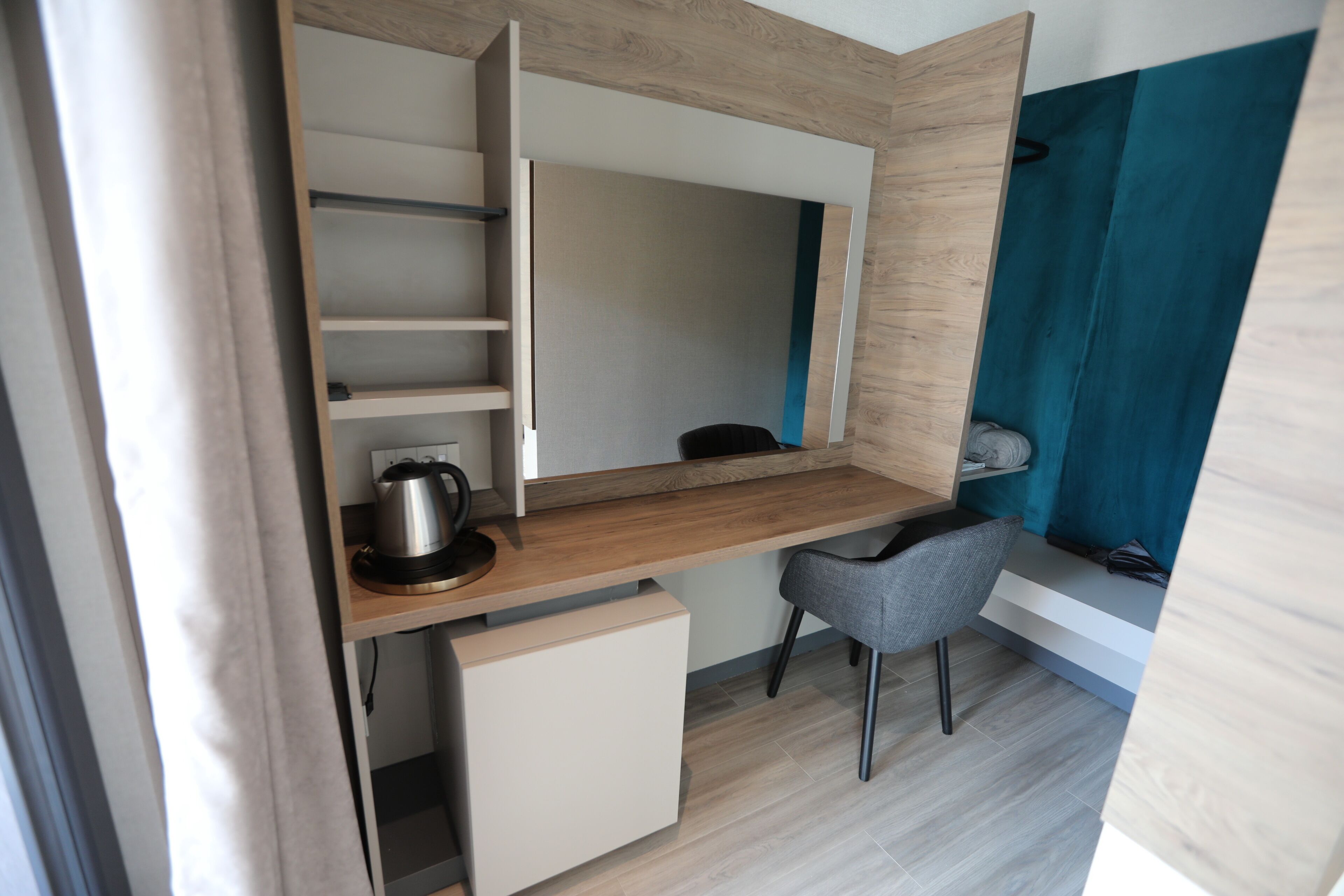 Una habitación compacta y moderna, con escritorio integrado, una silla y una pequeña zona de kitchenette.