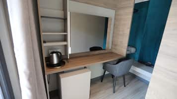 Una habitación compacta y moderna, con escritorio integrado, una silla y una pequeña zona de kitchenette.