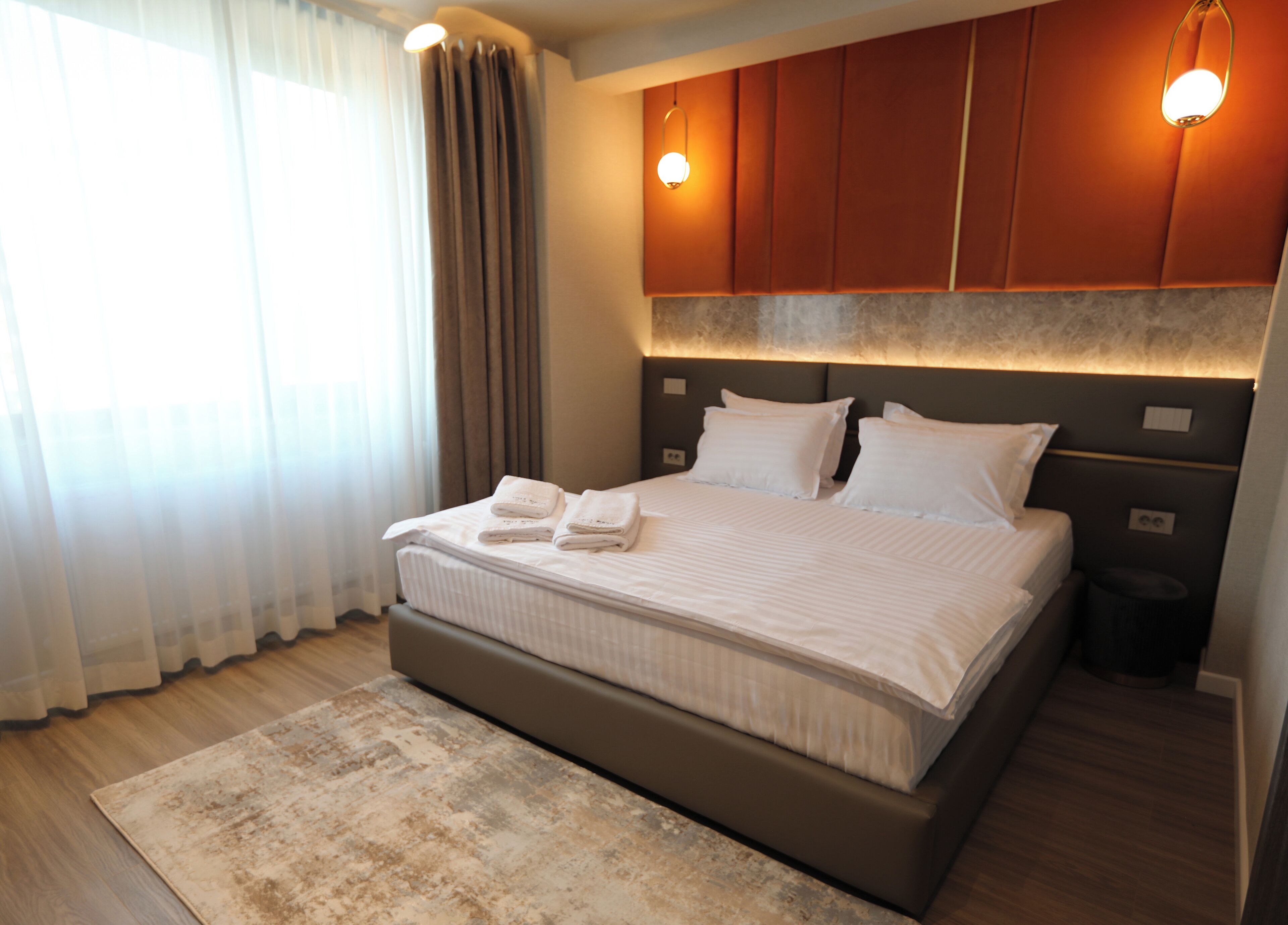 Una habitación de hotel moderna con una cama grande, un cabecero con iluminación integrada, una mesita de noche y un velador.