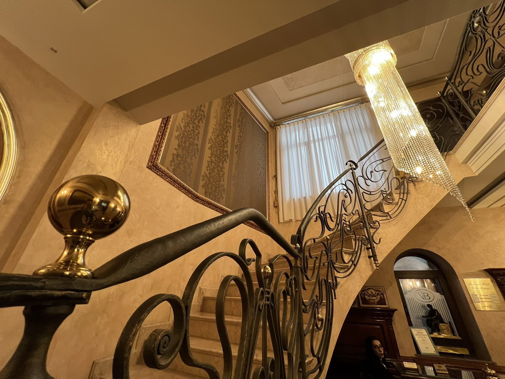 A grand staircase with ornate metal railings and a chandelier.