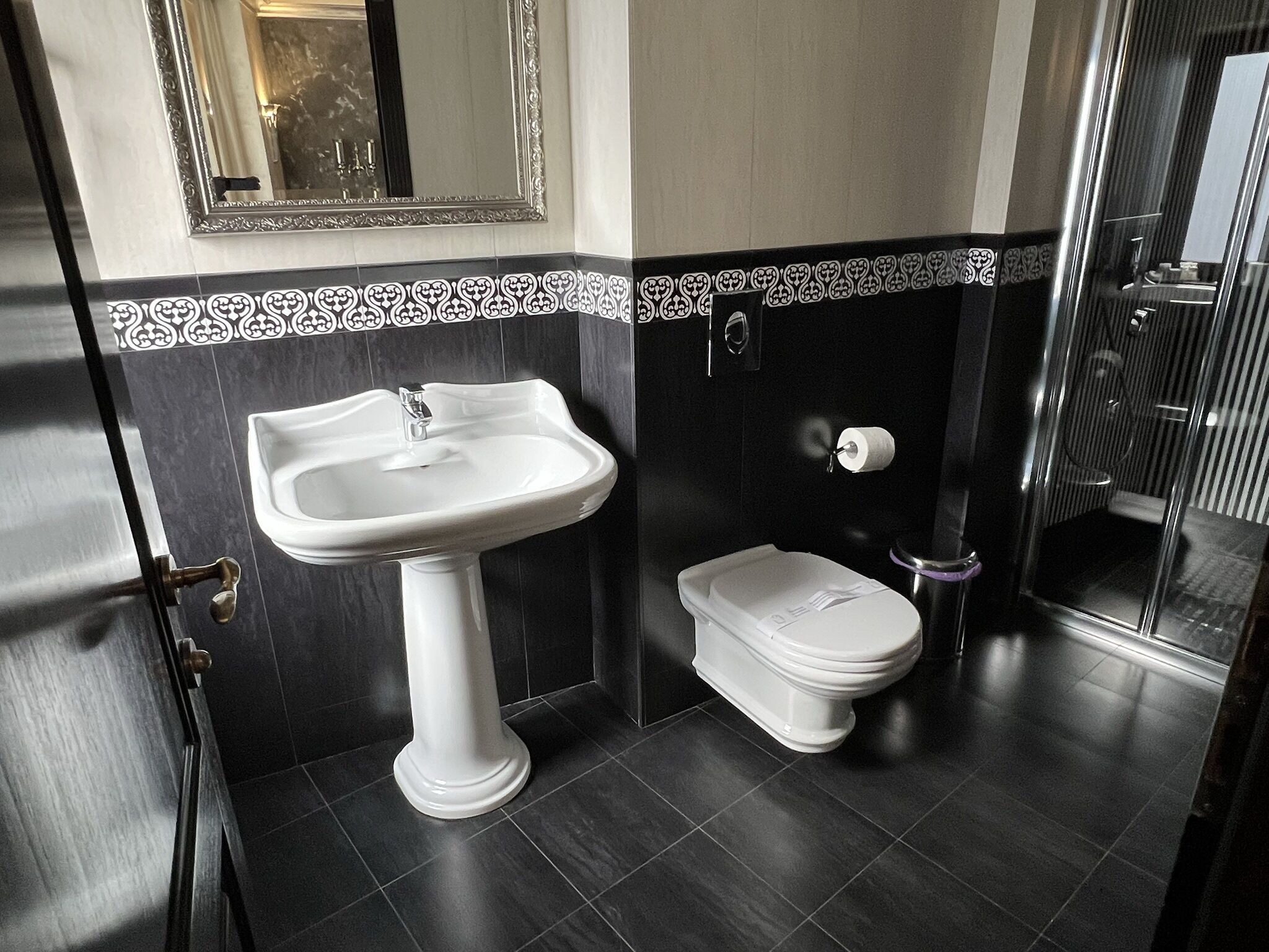 A bathroom with a pedestal sink, toilet, and a shower area.