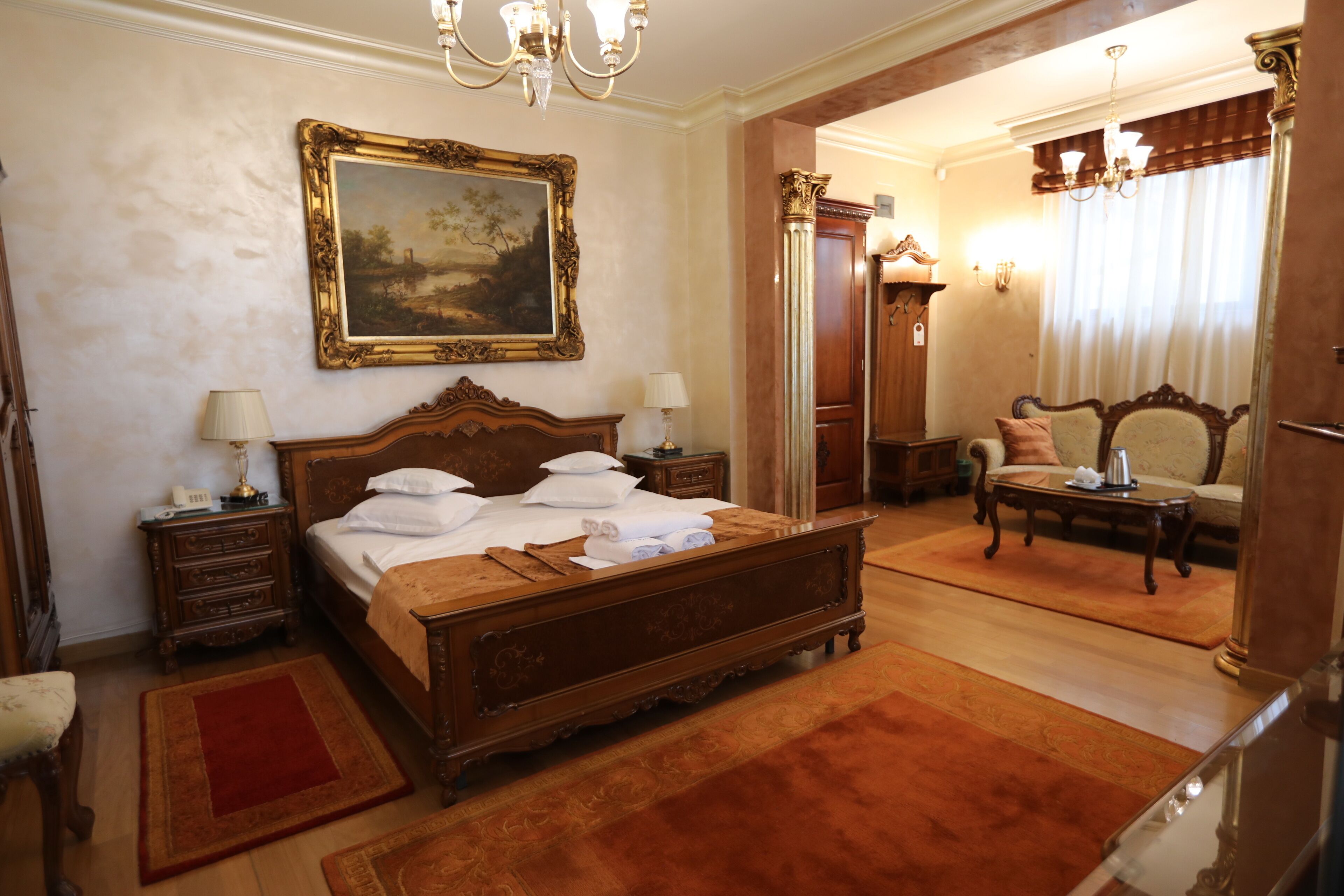 A spacious bedroom with a large bed, a wooden nightstand, a dresser, a chair, and a desk.
