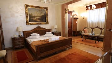 A spacious bedroom with a large bed, a wooden nightstand, a dresser, a chair, and a desk.